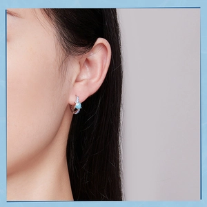 Close-up of S925 silver sea turtle stud earrings with blue accent on model's ear