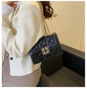 Detail of a black quilted leather crossbody bag with gold chain and metal buckle