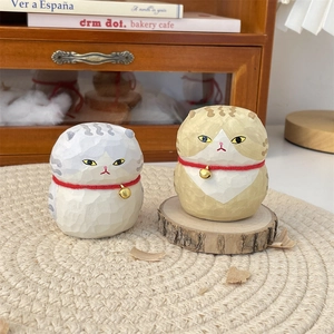 Detail of handcrafted wooden cat figurines with gold bells on rustic wooden stands