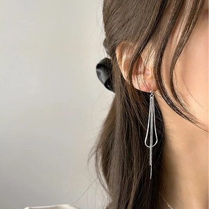 Close-up of model wearing long silver snake chain tassel earrings in minimalist style