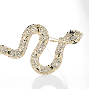 Macro shot of gold snake brooch with sparkling rhinestones and black gem eyes detail