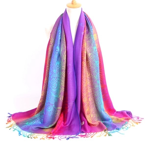 Detailed view of colorful jacquard scarf featuring peacock feather patterns and tassels