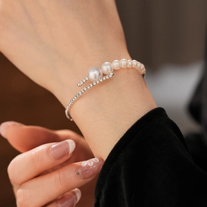 Detail view of a silver cuff bracelet with gradient pearls and diamonds on a model's wrist