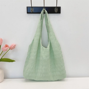 Detail of light green pleated fabric tote bag showing textured grain and wide strap