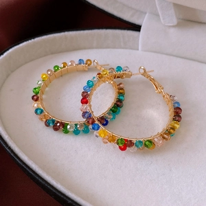 Detail of large hoop earrings with colorful glass beads and gold wire wrapping in a box