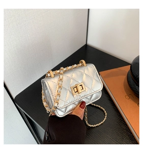 Macro detail of mini silver quilted handbag showing gold chain and metal twist lock