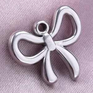 Macro shot of silver-toned stainless steel bow pendant on purple textured fabric