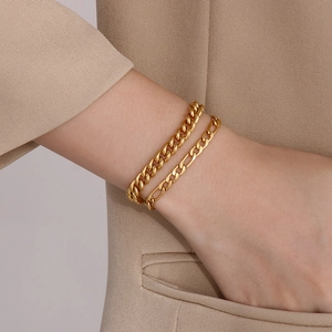 Gold-plated Cuban and Figaro layered bracelets set on wrist for minimalist fashion