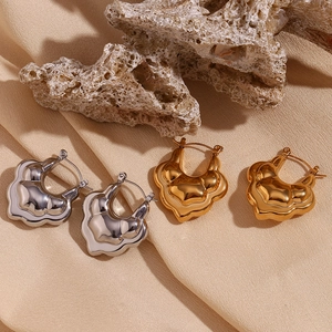 Detailed macro of gold and silver layered hollow lotus earrings on premium textured stone