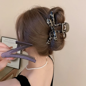 Detail shot of leopard print bow hair claw and purple geometric clip on model hair