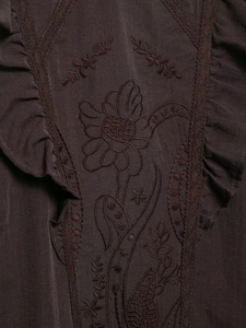Détail de broderie florale et de volants sur une chemise décontractée marron foncé