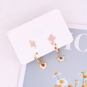 Macro shot of gold ear stud set with lightning, cross, heart, and star charms