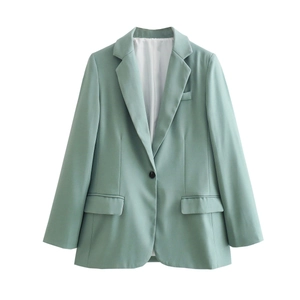 Detail of light green blazer showing single button closure and flap pockets on fabric