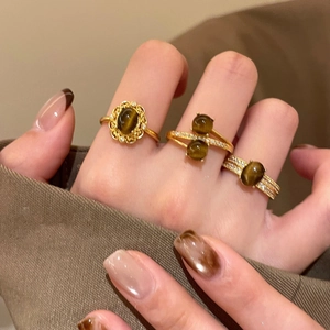 Dettaglio di anelli vintage placcati oro con occhio di tigre marrone e zirconi