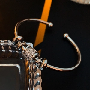 Close-up of a silver zircon open bangle resting on a glass edge with premium lighting