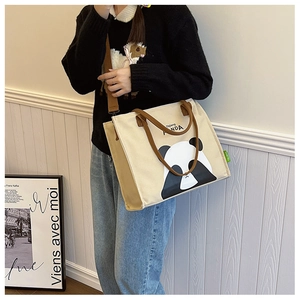 Detailed view of cream canvas tote bag with panda print and brown shoulder strap