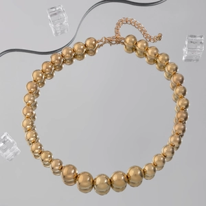 Men's hip hop chunky gold bead necklace with metallic spheres on reflective surface