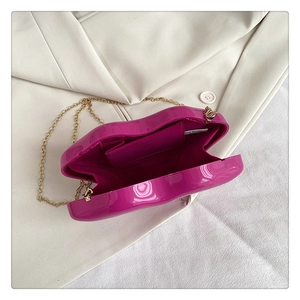 Detail of rose red lip-shaped acrylic clutch with gold chain on white suit background