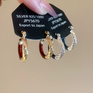 Close-up of vintage twisted enamel C-hoop earrings in gold-red and silver-blue finishes