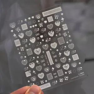 Close-up of 3D embossed nail stickers featuring white lace hearts, pearls, and bows