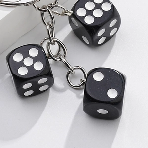 Close-up of three black plastic dice keychain with white dots and metal link chain