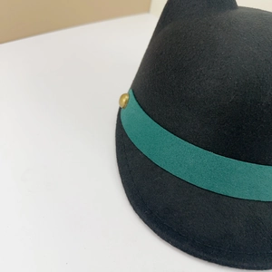 Detail of black wool equestrian hat with dark green ribbon and golden metallic button