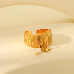 Close-up of gold plated stainless steel star ring with textured band and pearl charm