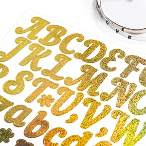 Macro shot of gold glitter uppercase and lowercase letter stickers for gift DIY cards