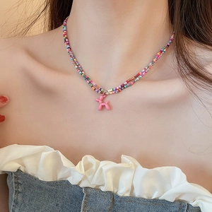 Detail of double-layer beaded necklace featuring a pink resin balloon dog pendant