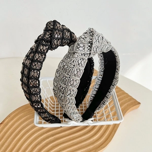 Close-up of knotted wide headbands in black and silver with metallic woven texture