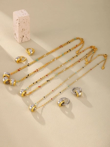 Detail of multi-layered beaded necklaces and earrings with engraved LOVE pendant on sand