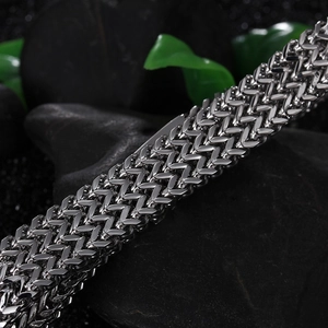 Detailed macro view of silver titanium steel dragon bone chain with woven texture on black stones