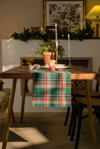 Close-up of red and green plaid table runner with festive Christmas decorations