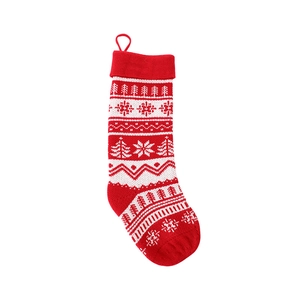 Red and white knitted Christmas stocking with snowflake and tree patterns on white background