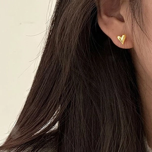 Close-up of heart-shaped 18k gold plated stainless steel earring worn on a model ear