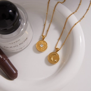 Luxurious 18k gold plated sun and moon pendant necklaces on white porcelain tray