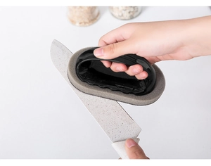 Macro shot of kitchen cleaning sponge brush with handle scrubbing a marble knife blade