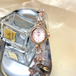 Detail of rose gold bracelet watch featuring floral links and large sparkling crystals