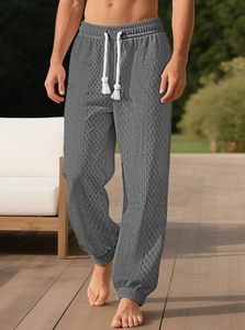 Détail du jogging en maille jacquard gris foncé avec texture losange et cordons blancs