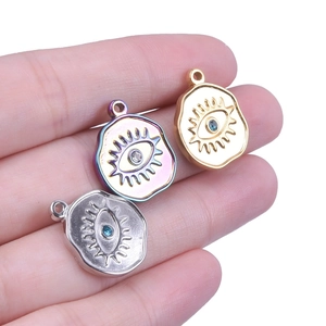 Macro shot of evil eye charms in gold, silver, and rainbow steel on fingers