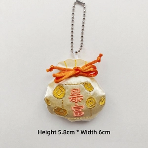 Vista detallada de una bolsa bordada de 5,8x6cm con borla y nudo naranja