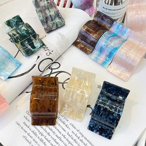 Close-up of acetic acid hair claws with marble textures on open book pages