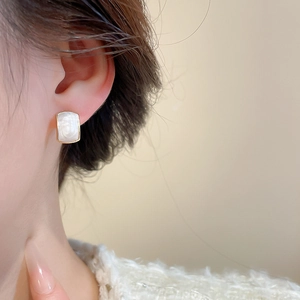 Close-up of a vintage rectangular white pearl earring with gold alloy frame on ear