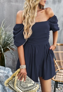 Detail of navy blue off-shoulder romper with puff sleeves and pleated shorts design