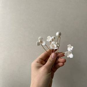 Set of six gold bridal hair pins featuring white ceramic flowers and elegant pearls