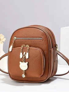 Brown lychee leather mini backpack with gold zippers and decorative cat pendant