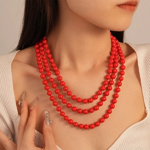 Detail of red faux pearl necklace featuring triple-layered beads and hand-knotted design