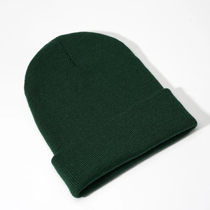 Close-up of a dark green ribbed knit beanie with a cuffed brim on white background