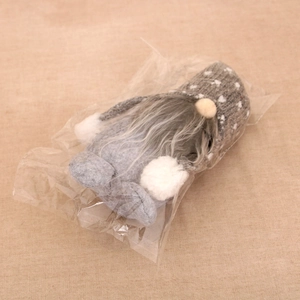 Close-up of a grey knitted Christmas gnome doll in a transparent protective bag