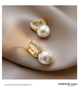 Close-up of elegant gold hoop earrings with zircon pavé and large white pearls